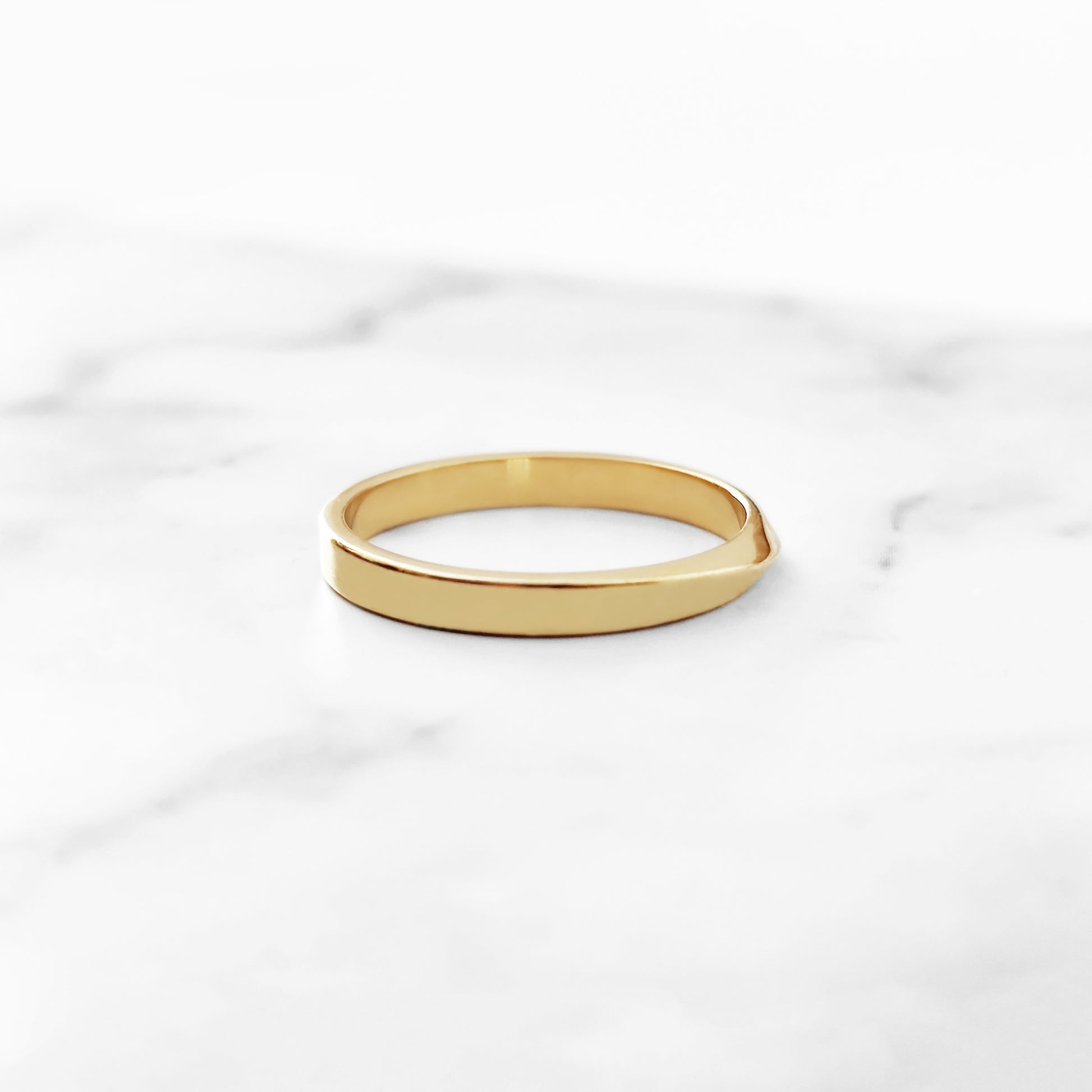 side view of a polished solid yellow gold thin mobius wedding ring 