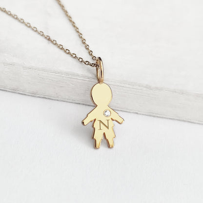 close up of a yellow gold necklace with tiny boy outline charm engraved with a monogram and set with tiny diamond