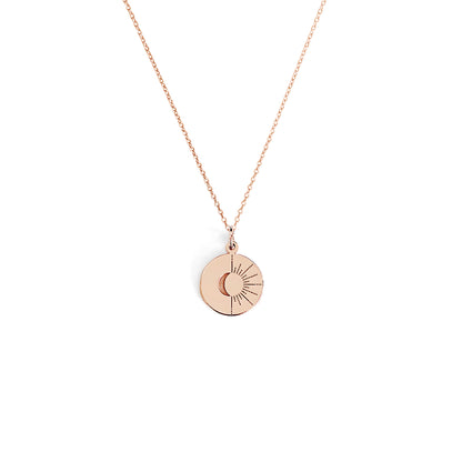 solid rose gold disc pendant necklace engraved with a crescent moon and sun rays on a white background