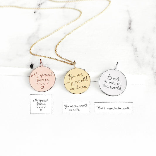 Three round pendants with personalized handwriting engravings on a marble background