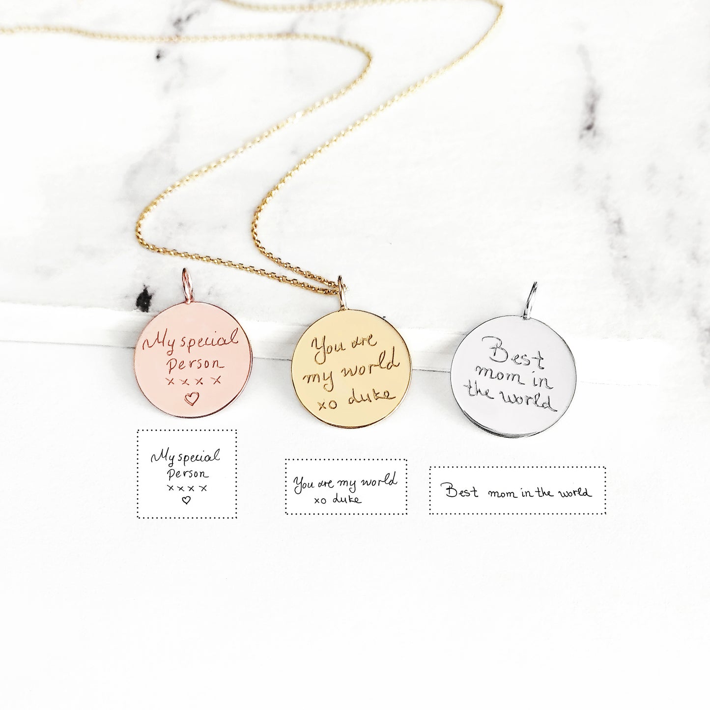 Three round pendants with personalized handwriting engravings on a marble background