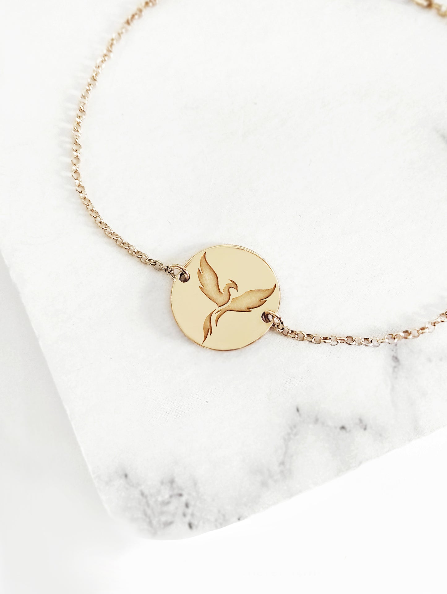 yellow gold bracelet with a 14mm disc charm engraved with a phoenix firebird rising