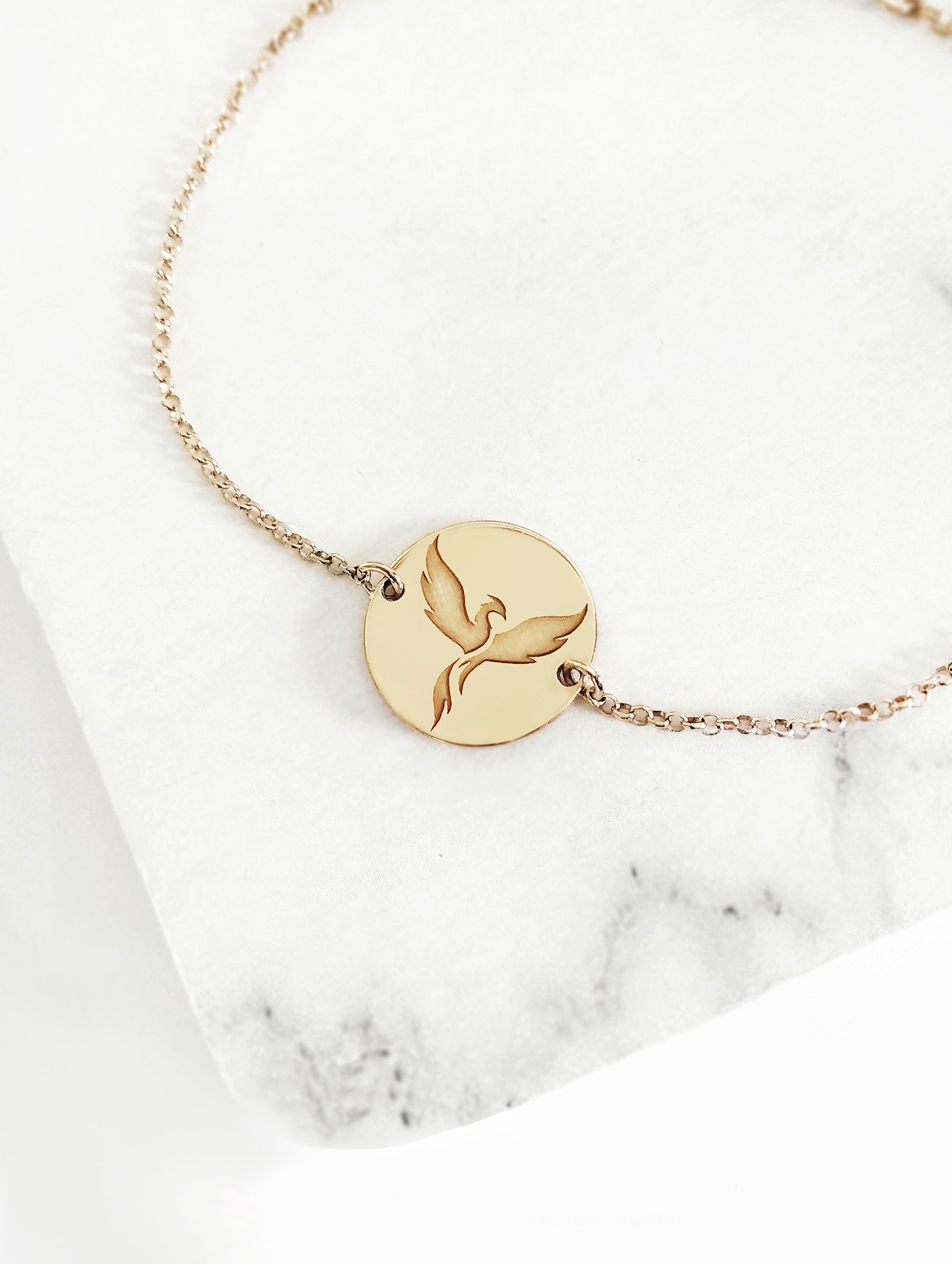 yellow gold bracelet with a 14mm disc charm engraved with a phoenix firebird rising