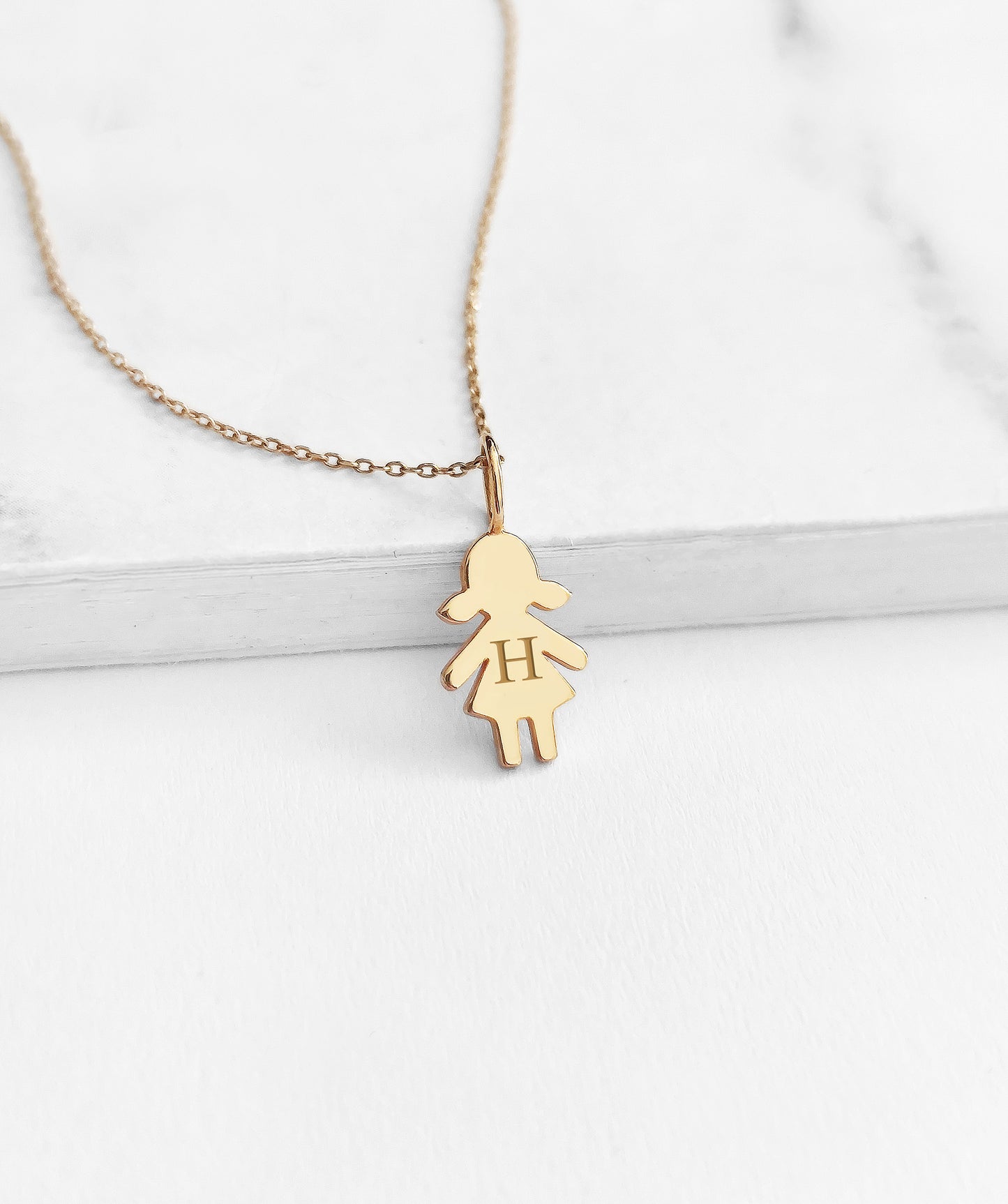 yellow gold necklace with tiny girl outline charm engraved with a monogram