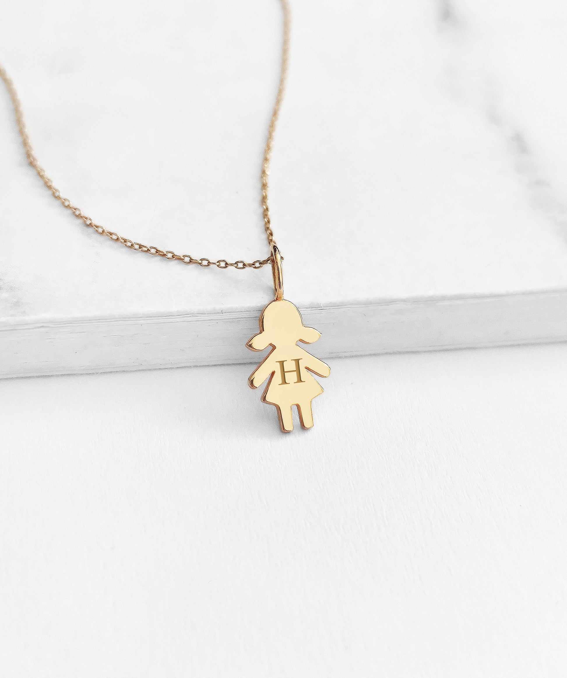 yellow gold necklace with tiny girl outline charm engraved with a monogram