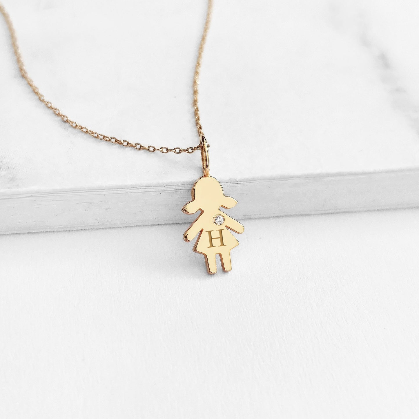 yellow gold necklace with tiny girl outline charm engraved with a monogram and set with tiny diamond