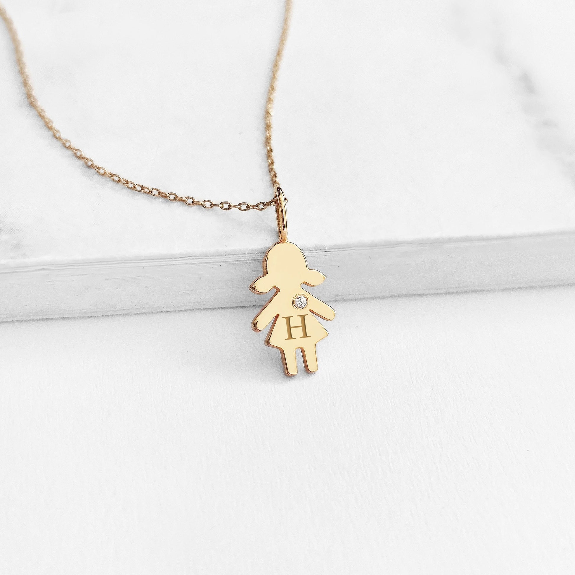 yellow gold necklace with tiny girl outline charm engraved with a monogram and set with tiny diamond
