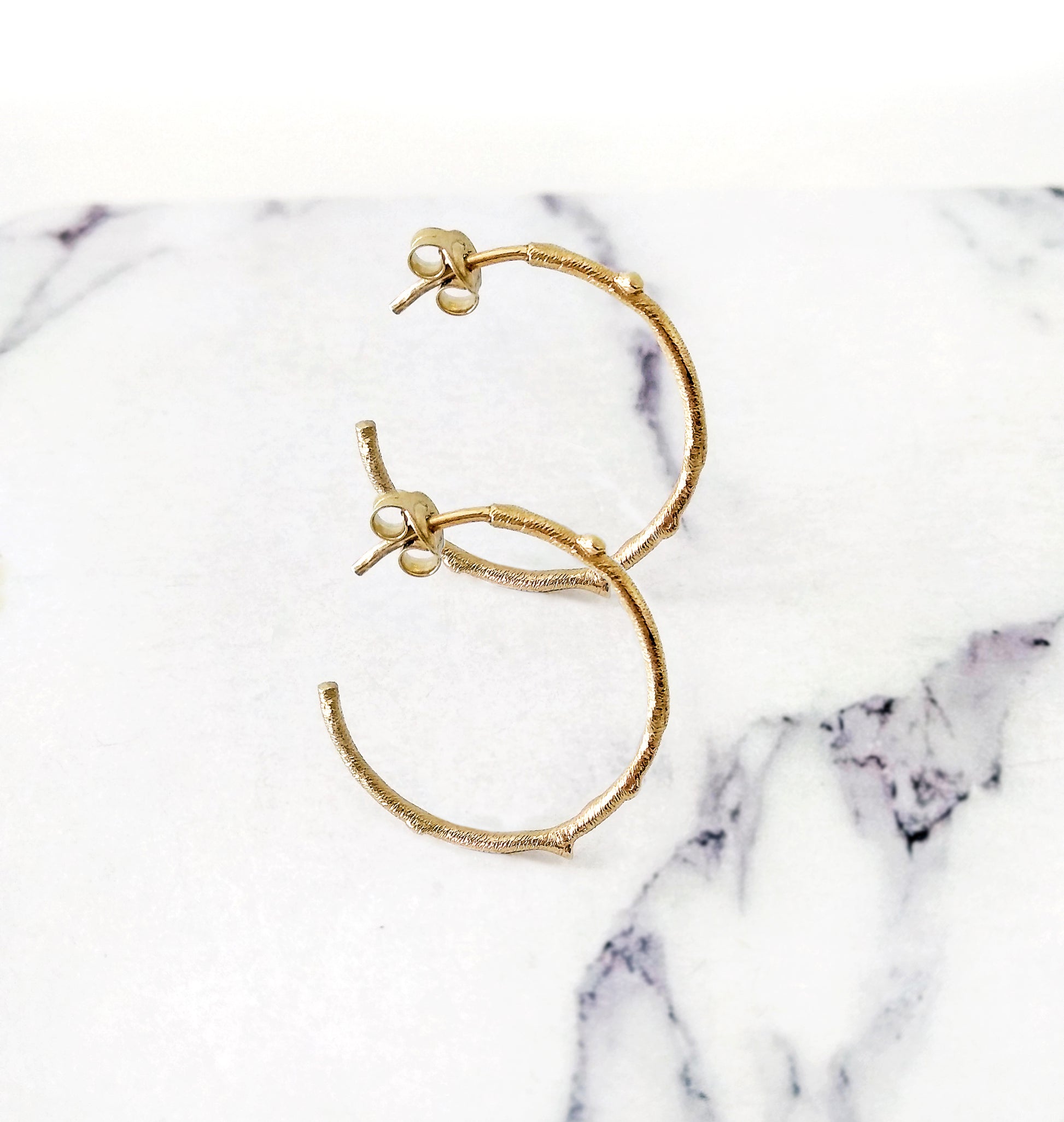 pair of solid gold hoop earrings with a twig branch like design
