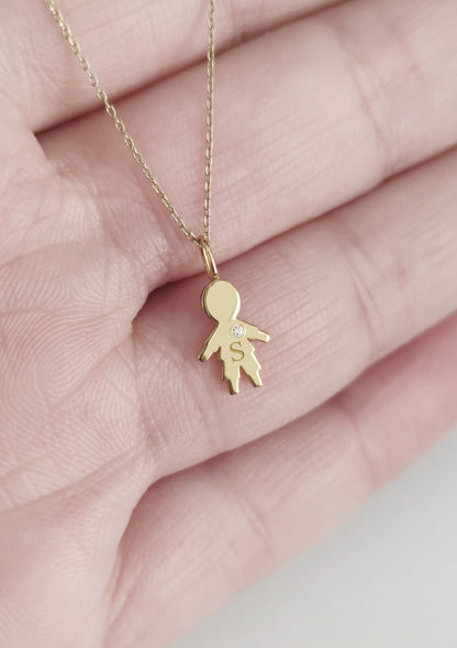 close up of a palm holding a gold necklace with a tiny boy outline charm set with a diamond and engraved with an initial for size reference