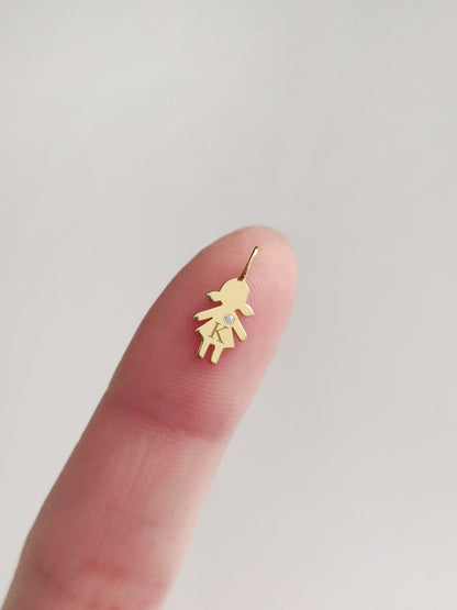 close up of a fingertip holding a tiny gold girl outline charm engraved with an initial and set with a tiny diamond for size reference