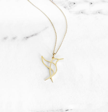 Close-up of a yellow gold necklace with a cutout origami style pendant in the shape of a hummingbird
