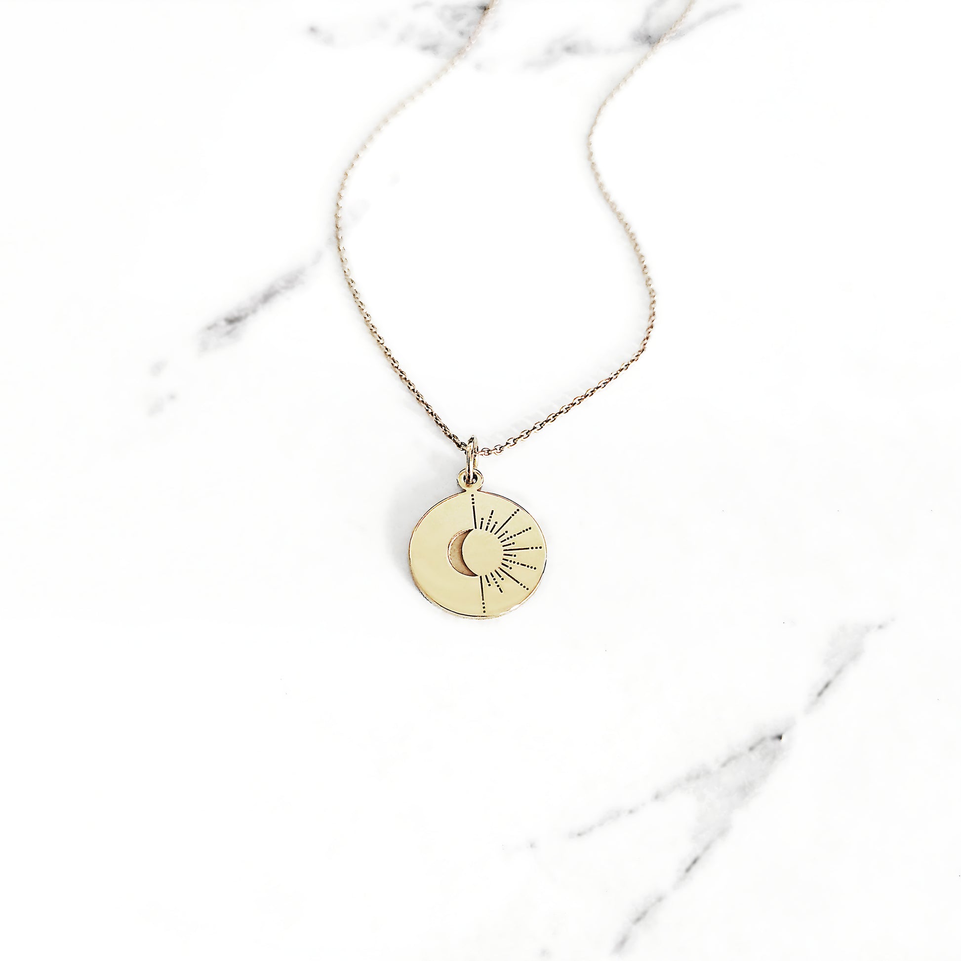 yellow gold disc pendant necklace engraved with a crescent moon and sun rays
